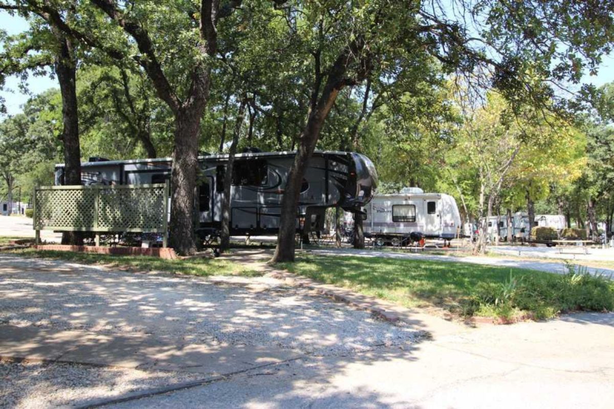 two RVs parked under the shade of trees at Fort Worth campground