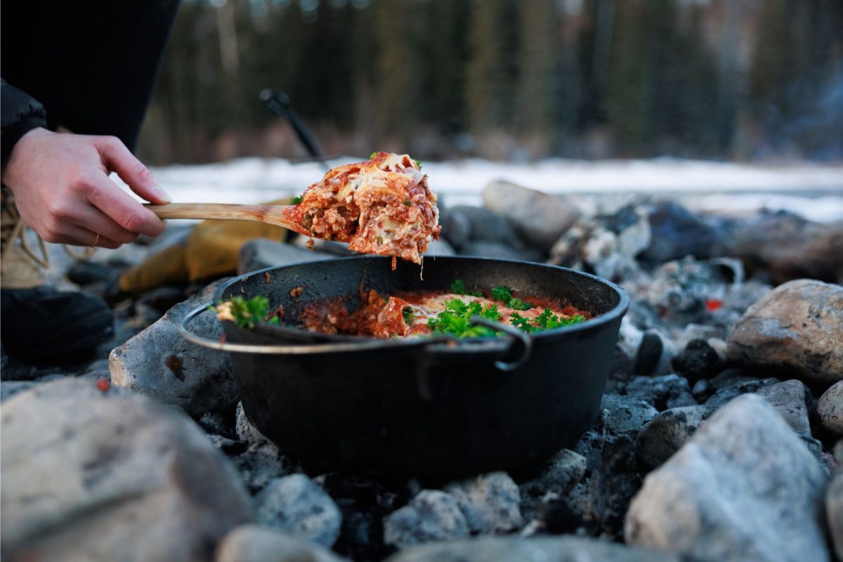 person holding a scoop of dutch oven lasagna 