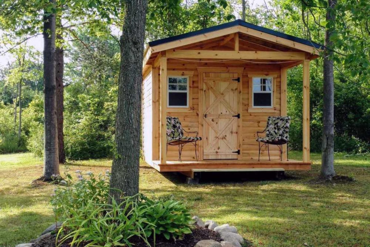 wood cabin with two patio chairs on grassy area at campground