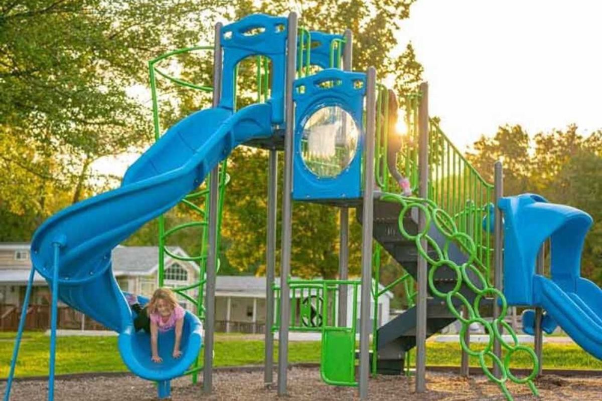 young girl coming down the slide at a playground at campground near NYC