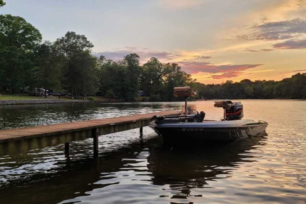 boat docked by pier on lake at sunset