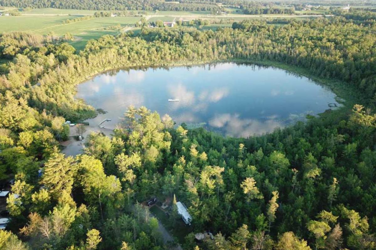 An aerial view of the water at Pine Grove Campground, surrounded by lush green trees. 