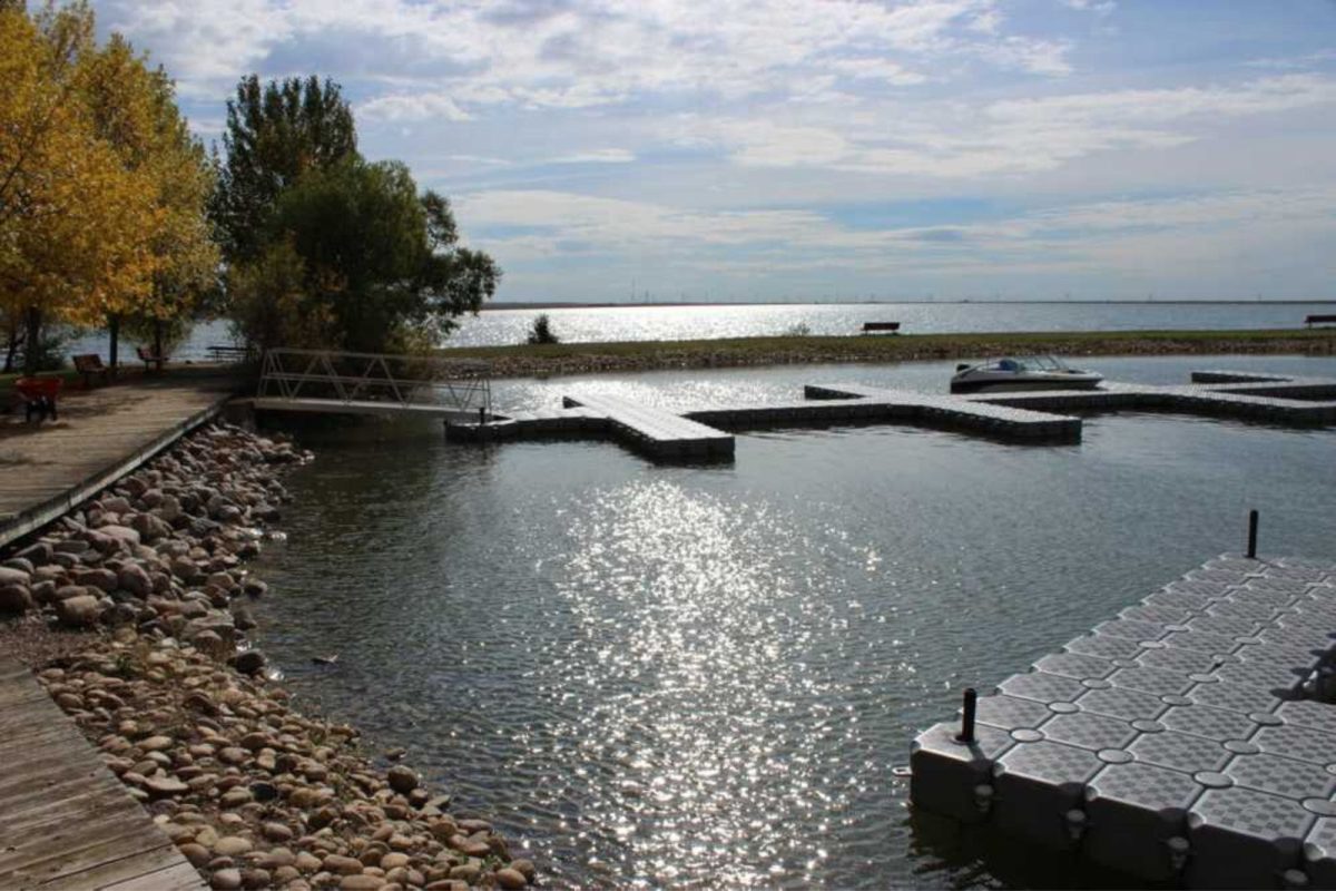 Boat docks on a shoreline with cloudy skies overhead. 