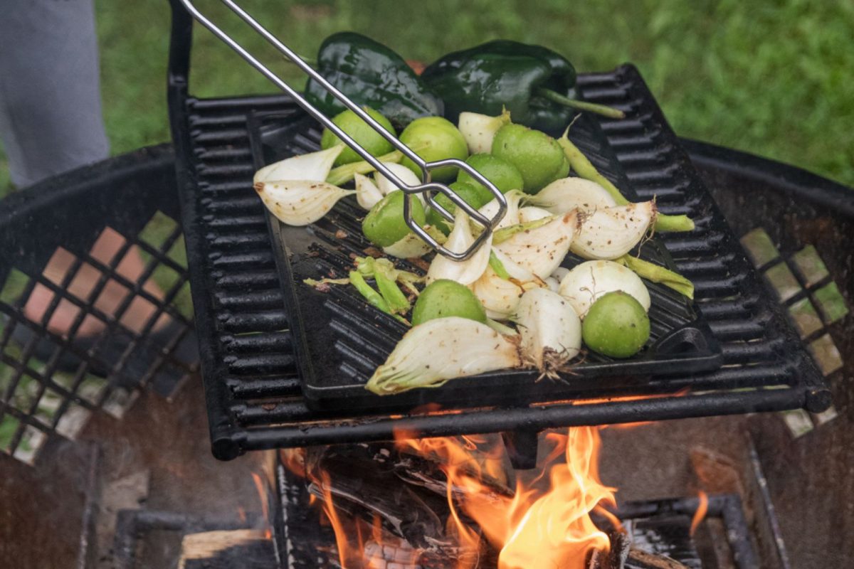 Grilled vegetables on a cast iron plate over an open flame at a campsite 