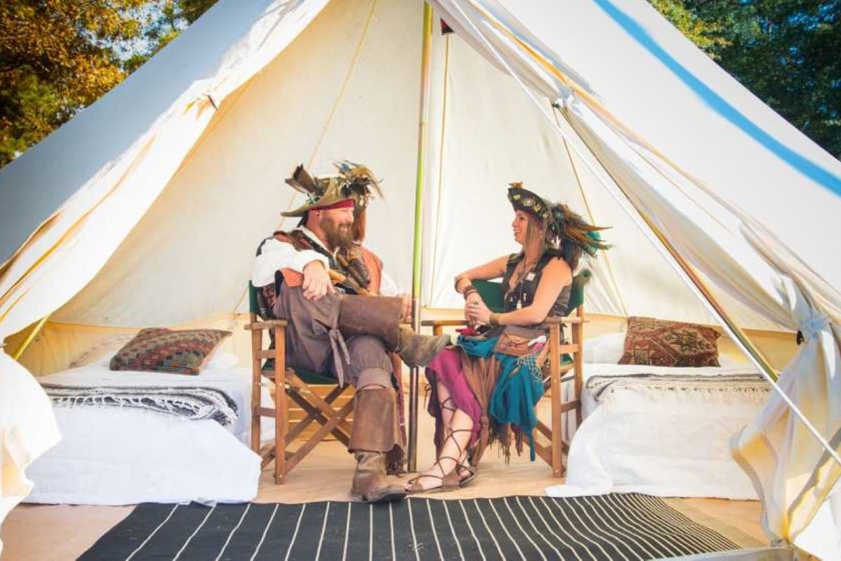 two people dressed in Renaissance Fair garb seated inside tent at Fields of New Market campground, a fall camping event