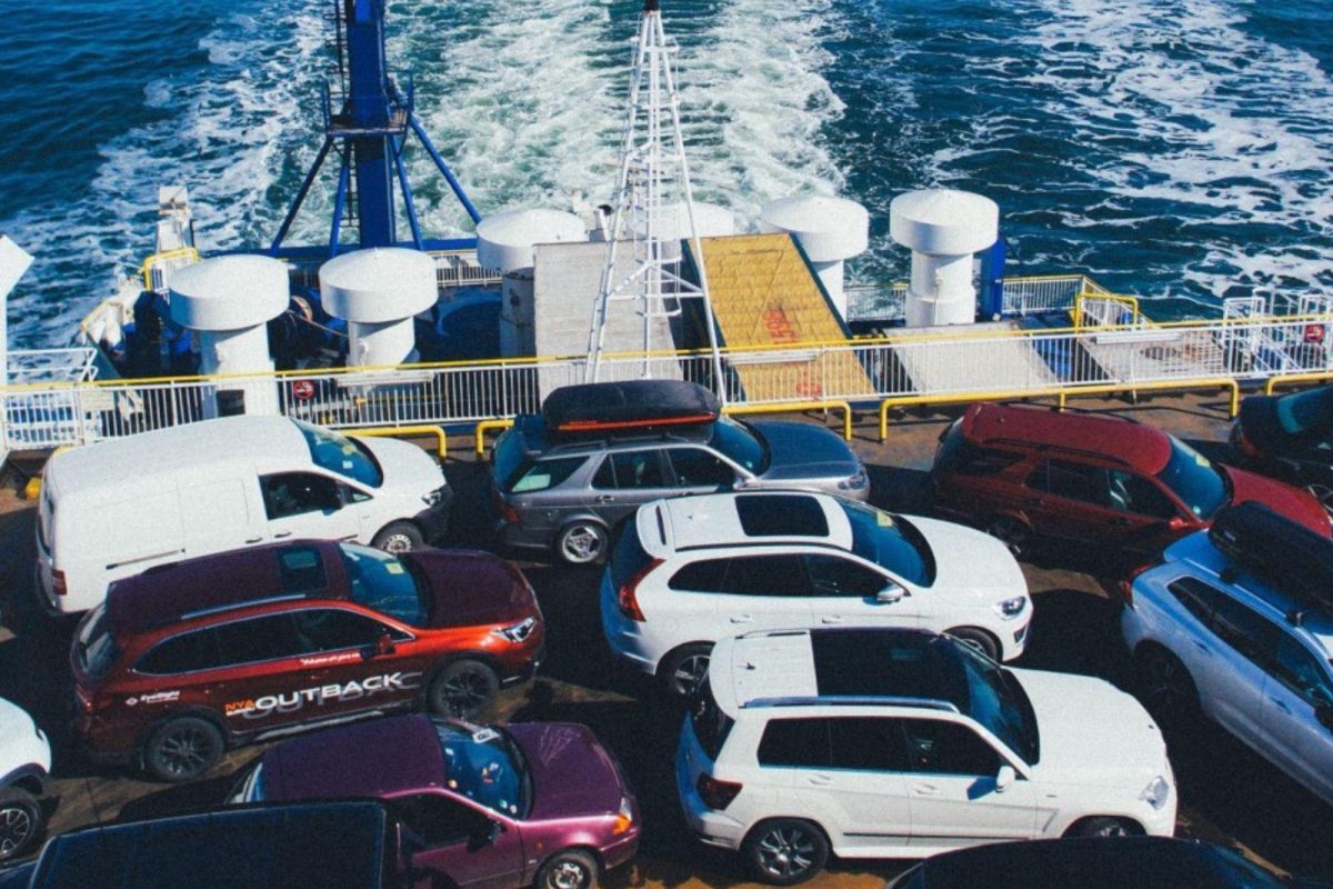 Many cars parked on a ferry boat being transported across the water. 