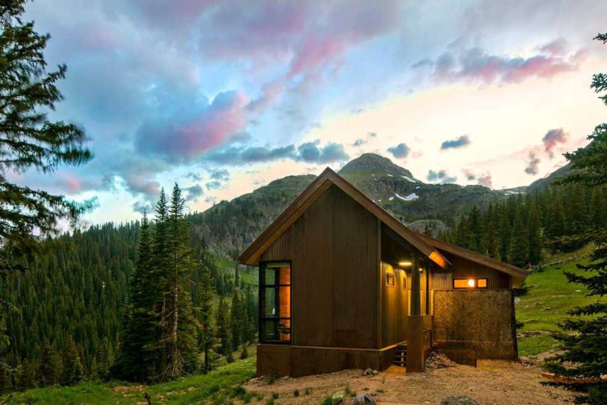 cabin on mountainside surrounded by pine trees