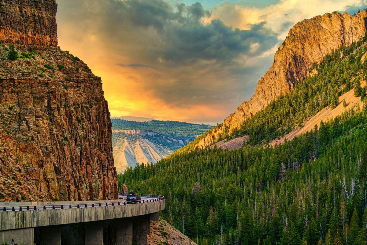 car driving on highway surrounded by Colorado mountains, top location for 2024 camping destinations