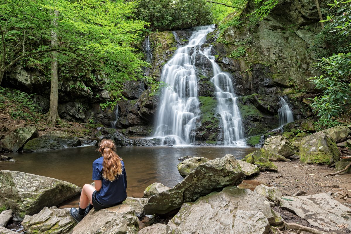 young woman viewing Spruce Flats Falls in Tremont of Great Smoky Mountains National Park itinerary