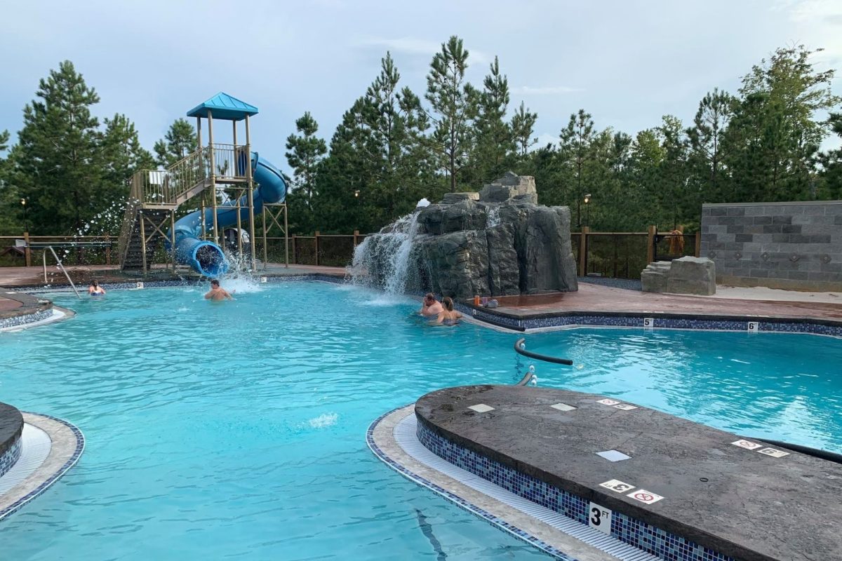 people swimming by pool with waterslide and waterfall at campground