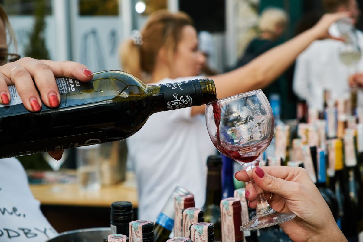 woman pours red wine into glass for festival-goer