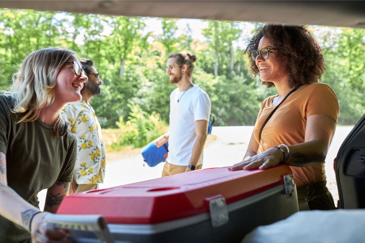 two friends carrying cooler out of camping car