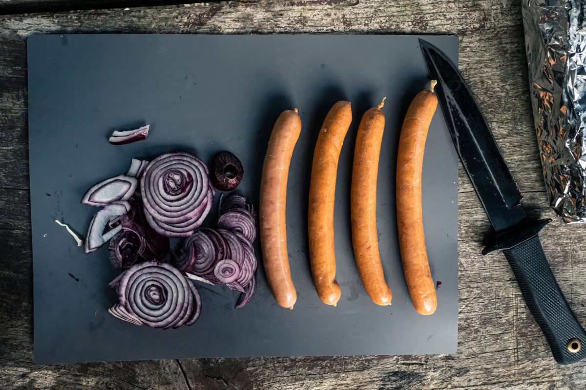 onion and sausages on cutting board with camping knife