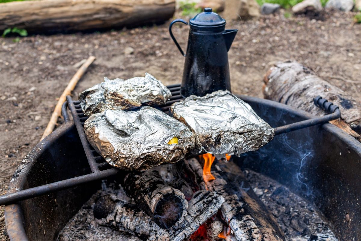 foil packets cooking over campfire with kettle