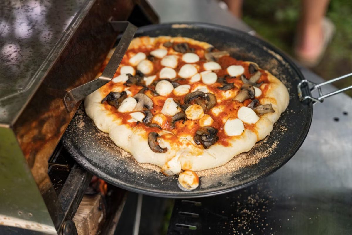 pulling out pizza from camping grill