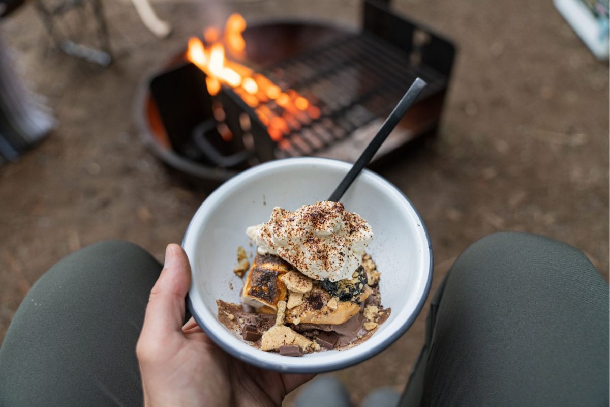 camper holding bowl of s'more sundae next to camping grill