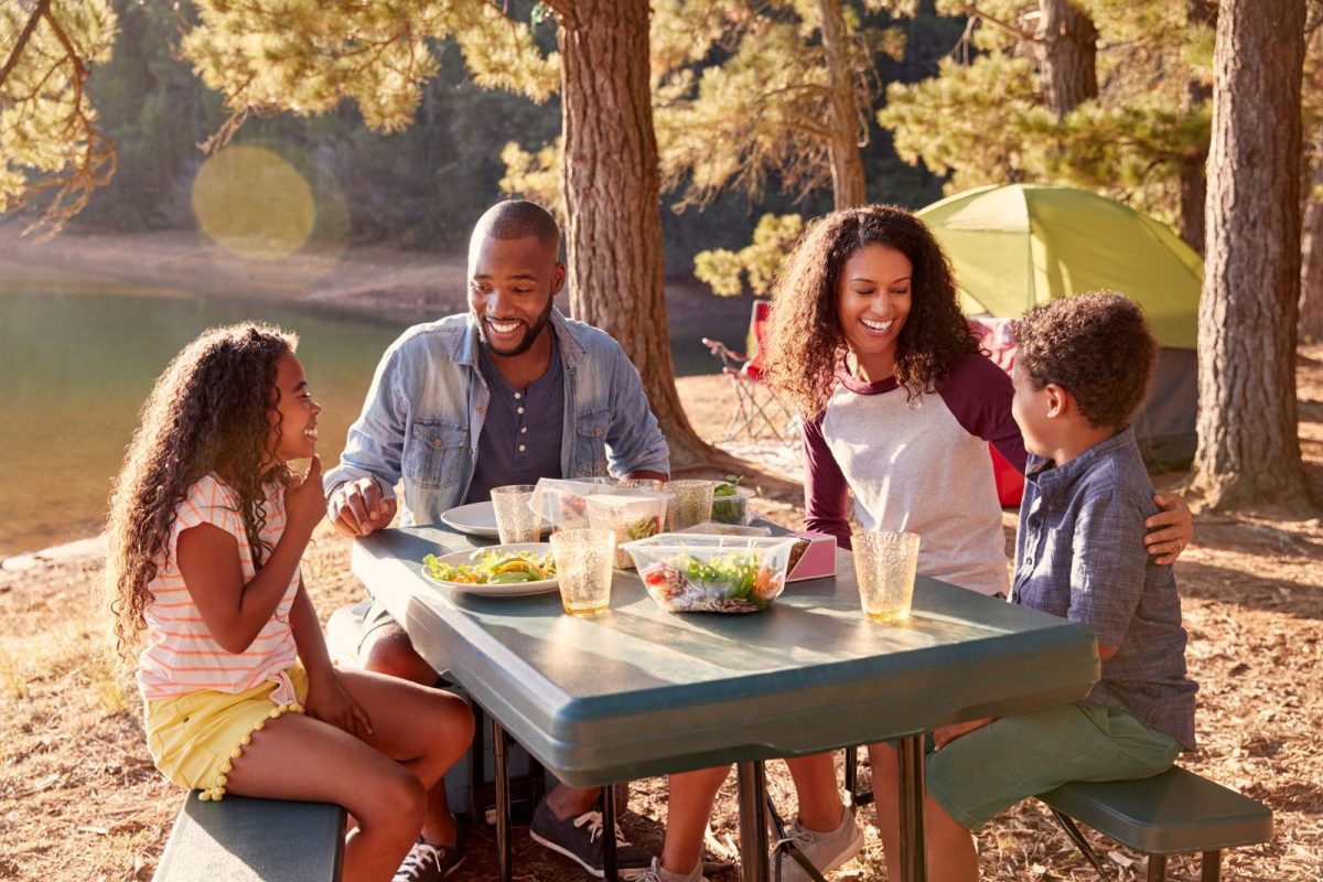 family relaxes while camping while having lunch by their tent