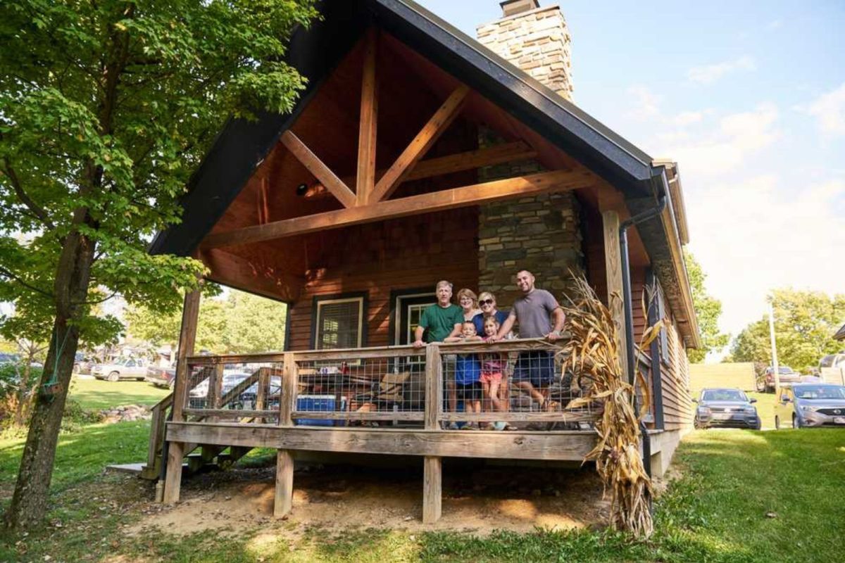 happy family standing on porch of campground cabin at Whispering Hills Jellystone Park