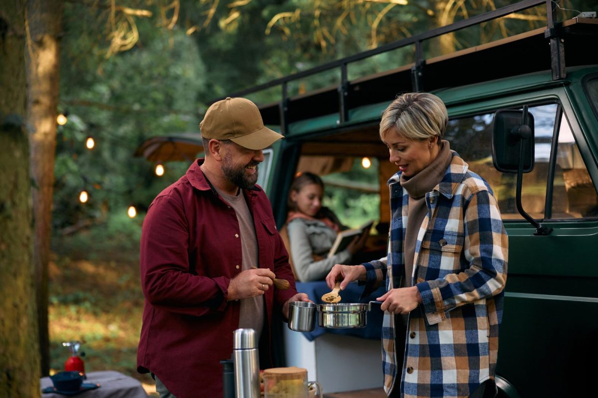 happy parents cooking in forest during fall or winter camping trip