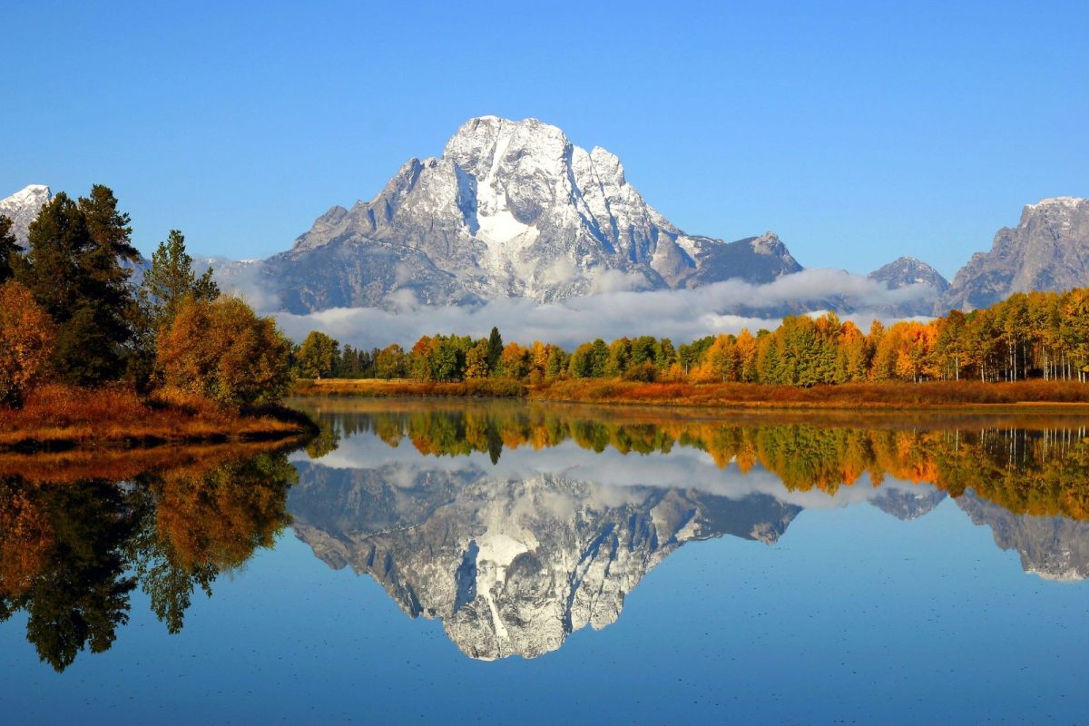 Teton Mountain range and fall trees reflected on lake at Grand Teton National Park, fall camping destination