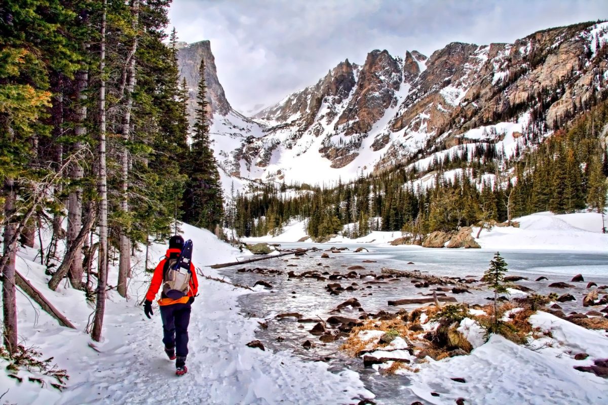 hiker walking by frozen river in Rocky Mountain National Park during winter camping trip