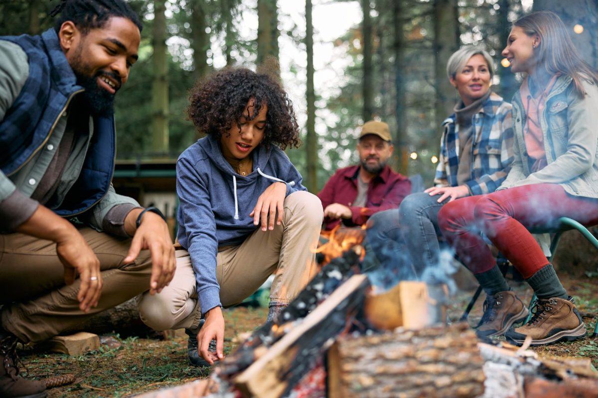 young Black man making fire with his father and family members