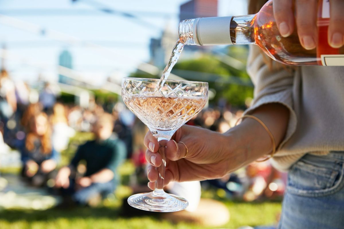 person pouring sparkling wine at outdoor festival for lovers of camping events