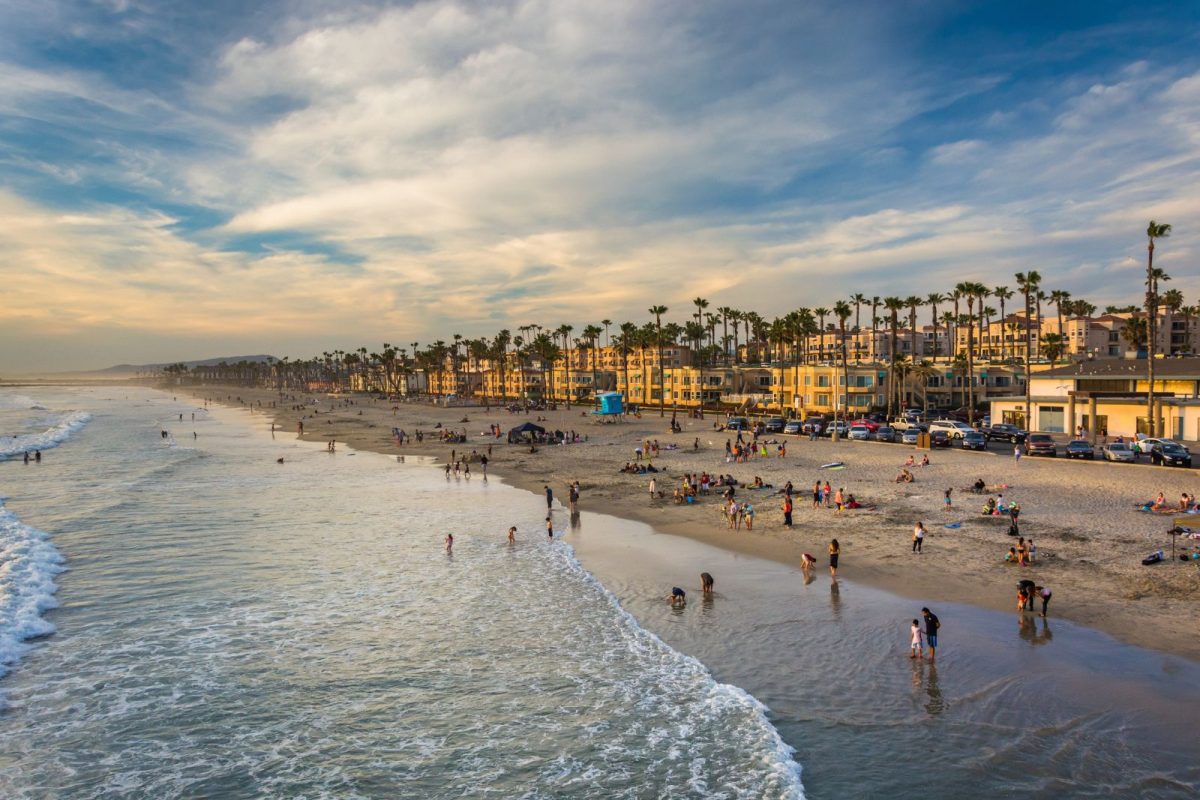 people on Oceanside beach from pier during spring break