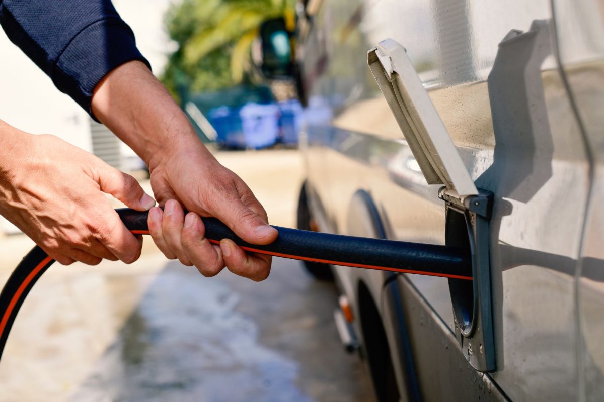 man's hands holding winter RV camping accessory water hose to fill up campervan